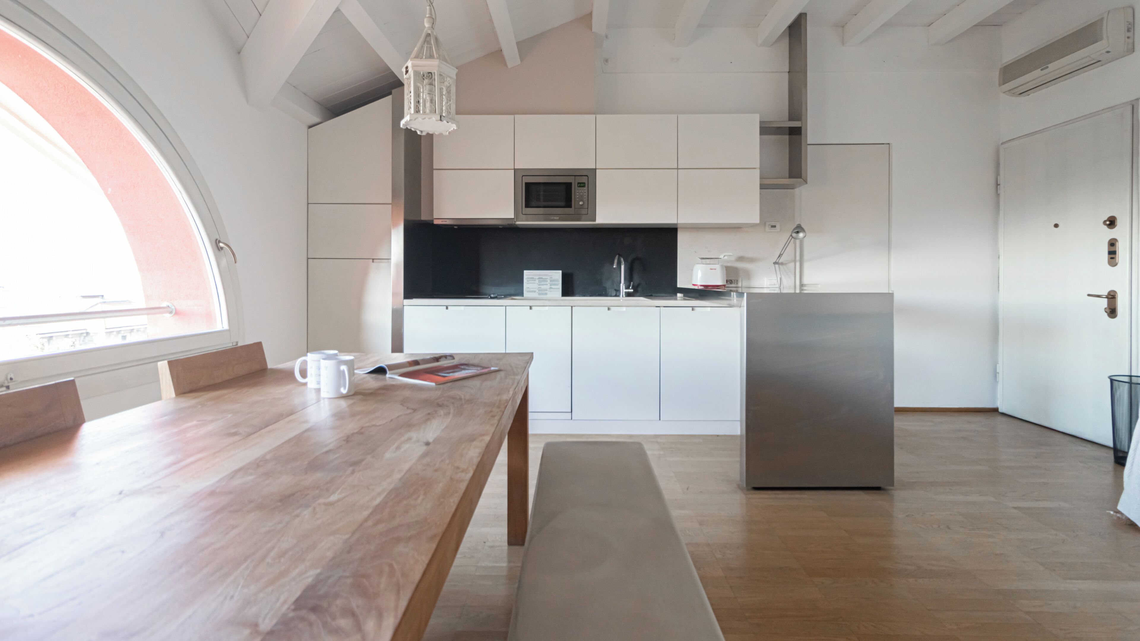 Una cocina moderna con armarios blancos, un refrigerador de acero inoxidable y una mesa de comedor de madera.