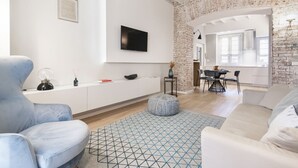 A modern living room with a white sofa, a blue armchair, and a geometric patterned rug. - Easylife - Beautiful apartment in Sarpi (Milano)