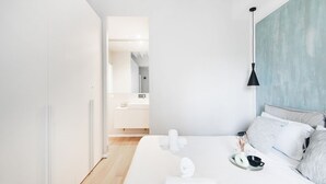 A modern hotel room with a large bed, a bedside table with a tray of toiletries, and a view of the bathroom. - Easylife - Beautiful apartment in Sarpi (Milano)