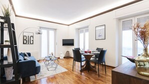 Una sala de estar moderna con sofá, mesa de centro y comedor con sillas y televisión.