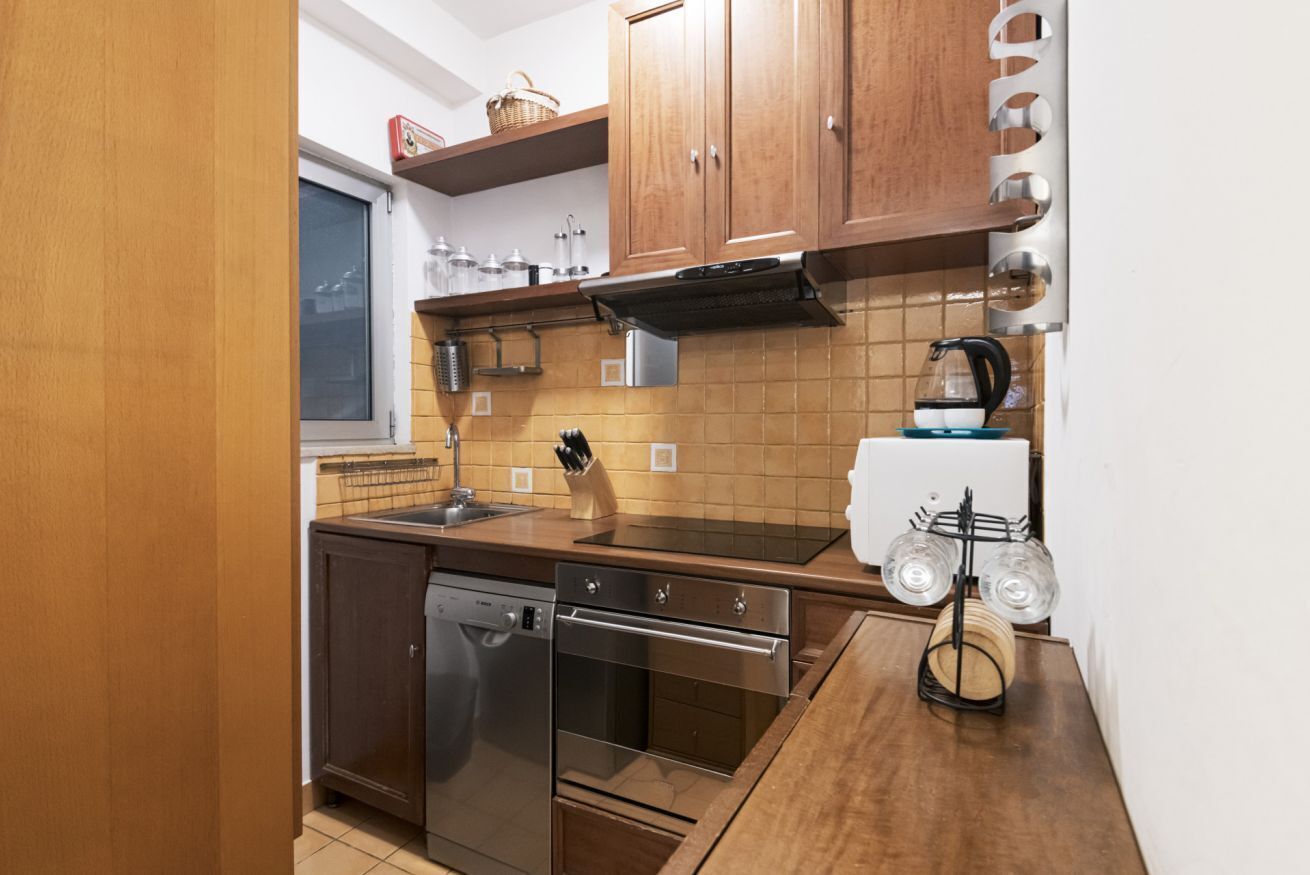 A compact kitchen with wooden cabinets, a dishwasher, an oven, and a coffee maker.