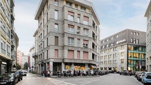 Un edificio de varios pisos con espacio comercial en la planta baja y un estacionamiento.