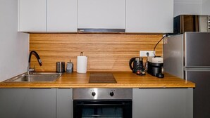 Moderni keittiö, jossa on puinen työtaso, ruostumattomasta teräksestä valmistetut kodinkoneet ja sisäänrakennettu uuni.