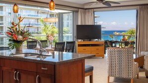 Ein modernes Hotelzimmer mit Balkon, großem Fernseher, Essbereich und Küche.