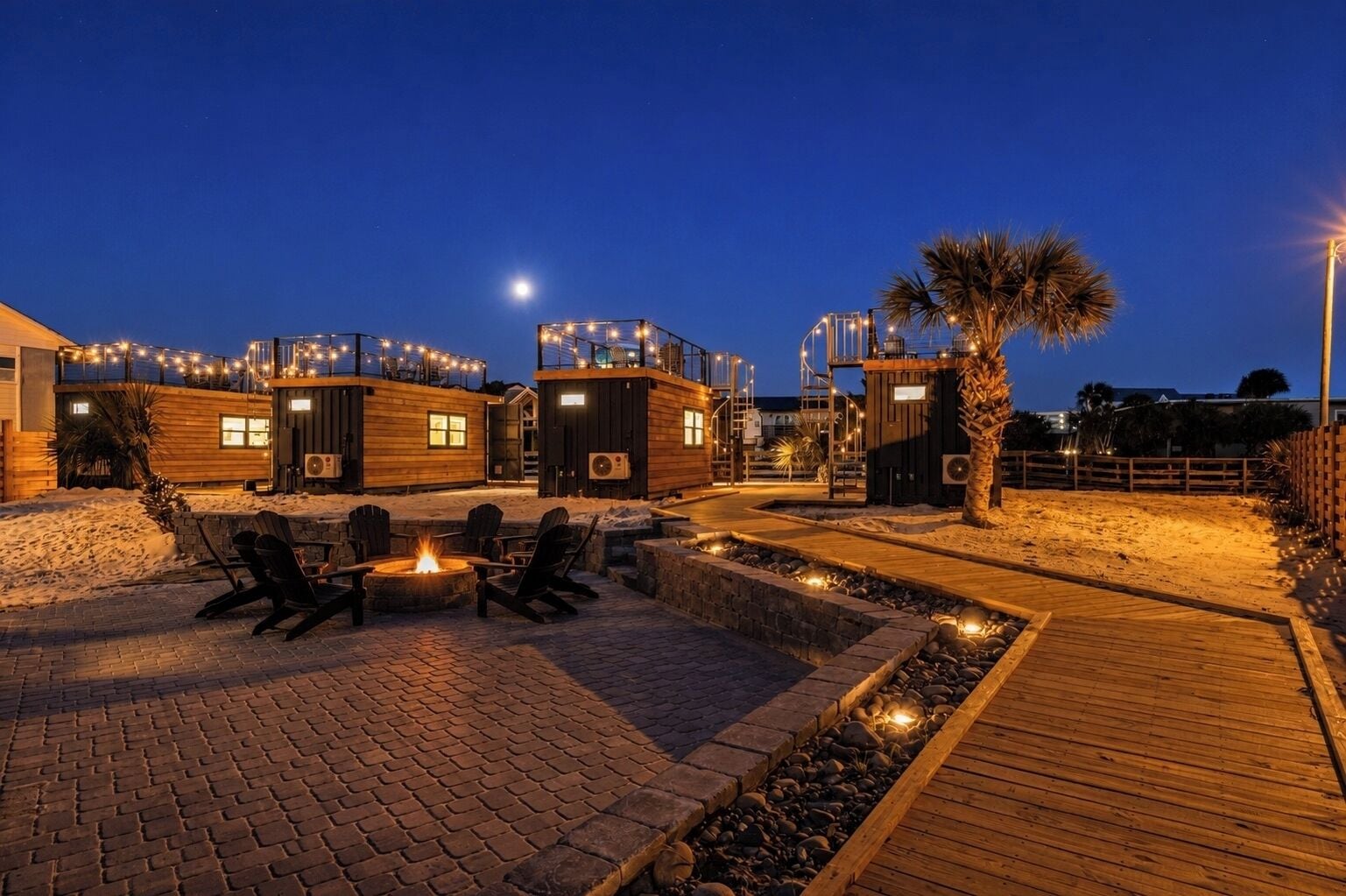 Un complejo turístico con asientos al aire libre, una fogata y una terraza de madera.
