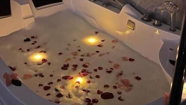 A bathtub with rose petals and candles, marble walls, and a black towel. - qimampark albaha7 (Al Baha)