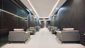 A modern interior with a central corridor, seating areas on both sides, and a glass wall on one side. - qimampark albaha7 (Al Baha)