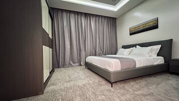 Een moderne hotelkamer met een groot bed, nachtkastje, kledingkast en een plafondlamp.