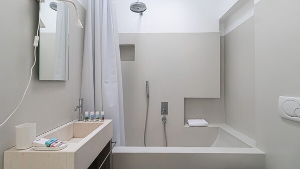 A modern bathroom with a sink, mirror, shower, and a towel rack.