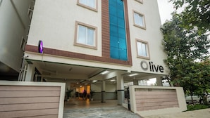 Entrada de un edificio con un cartel que indica 'live', un paseo techado y un camino de entrada con puerta de reja.
