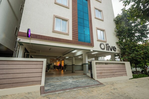 L'ingresso di un edificio con un cartello che indica 'live', una tettoia e un viale d'accesso recintato.
