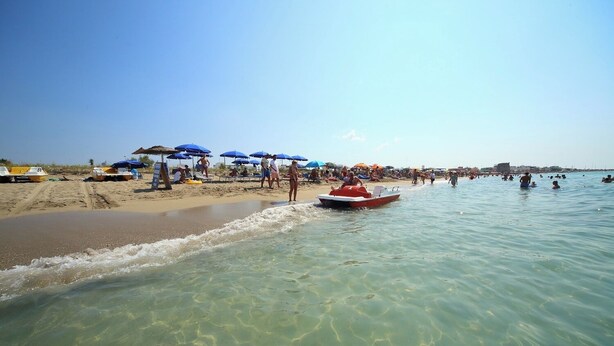 A beach with clear shallow waters, boats, and umbrellas. - Vacation Home Aphrodite Torre Mozza (Torre Mozza)
