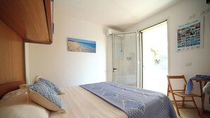 A bedroom with a bed, a chair, a glass door leading to a balcony, and a poster on the wall. - Vacation Home Aphrodite Torre Mozza (Torre Mozza)