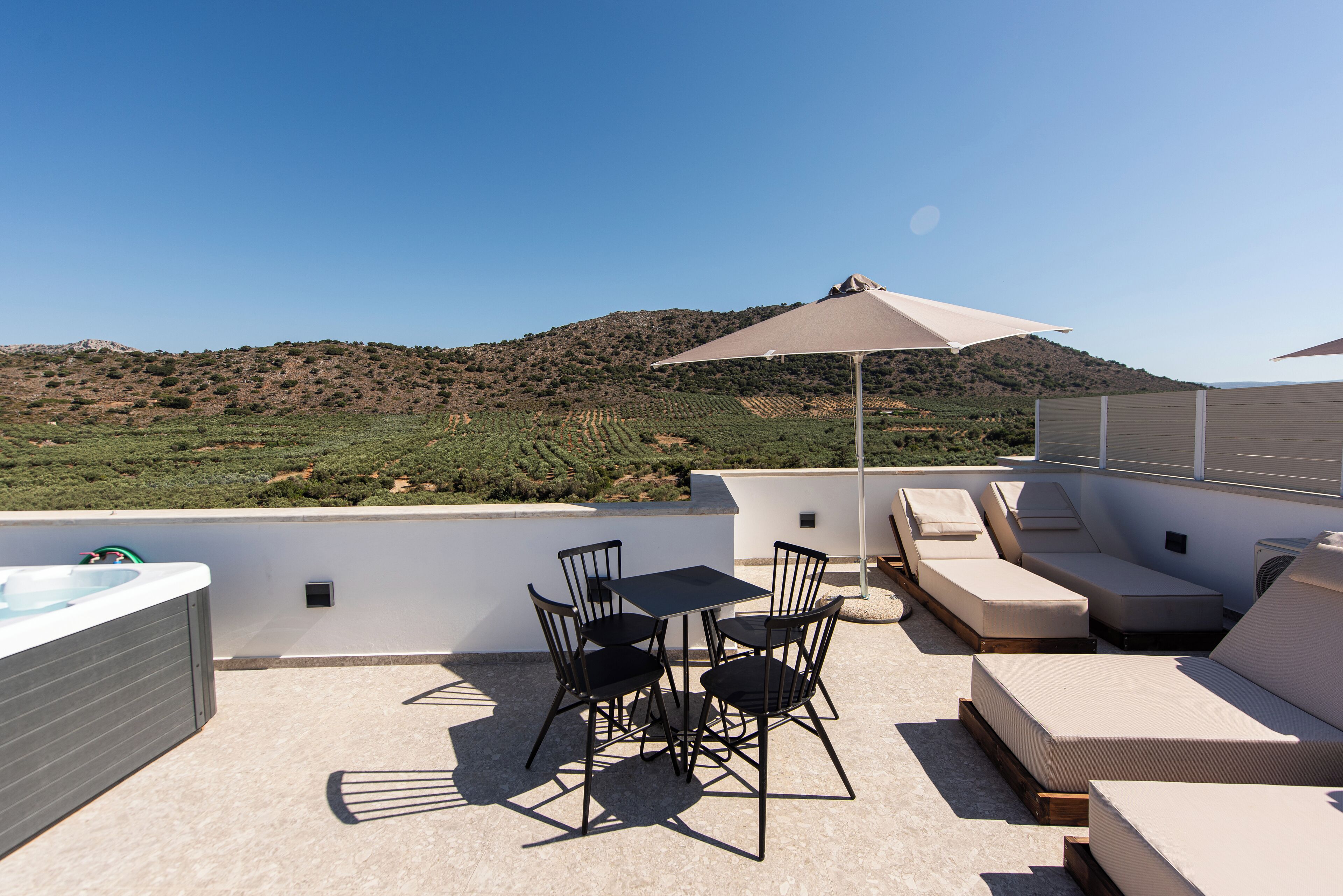Una terraza en la azotea con mesa y sillas, un sofá y un gran paraguas.