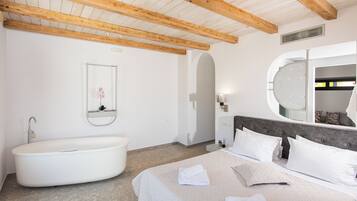 A bedroom with a large bed, a built-in bathtub, a round mirror, and a wooden ceiling.