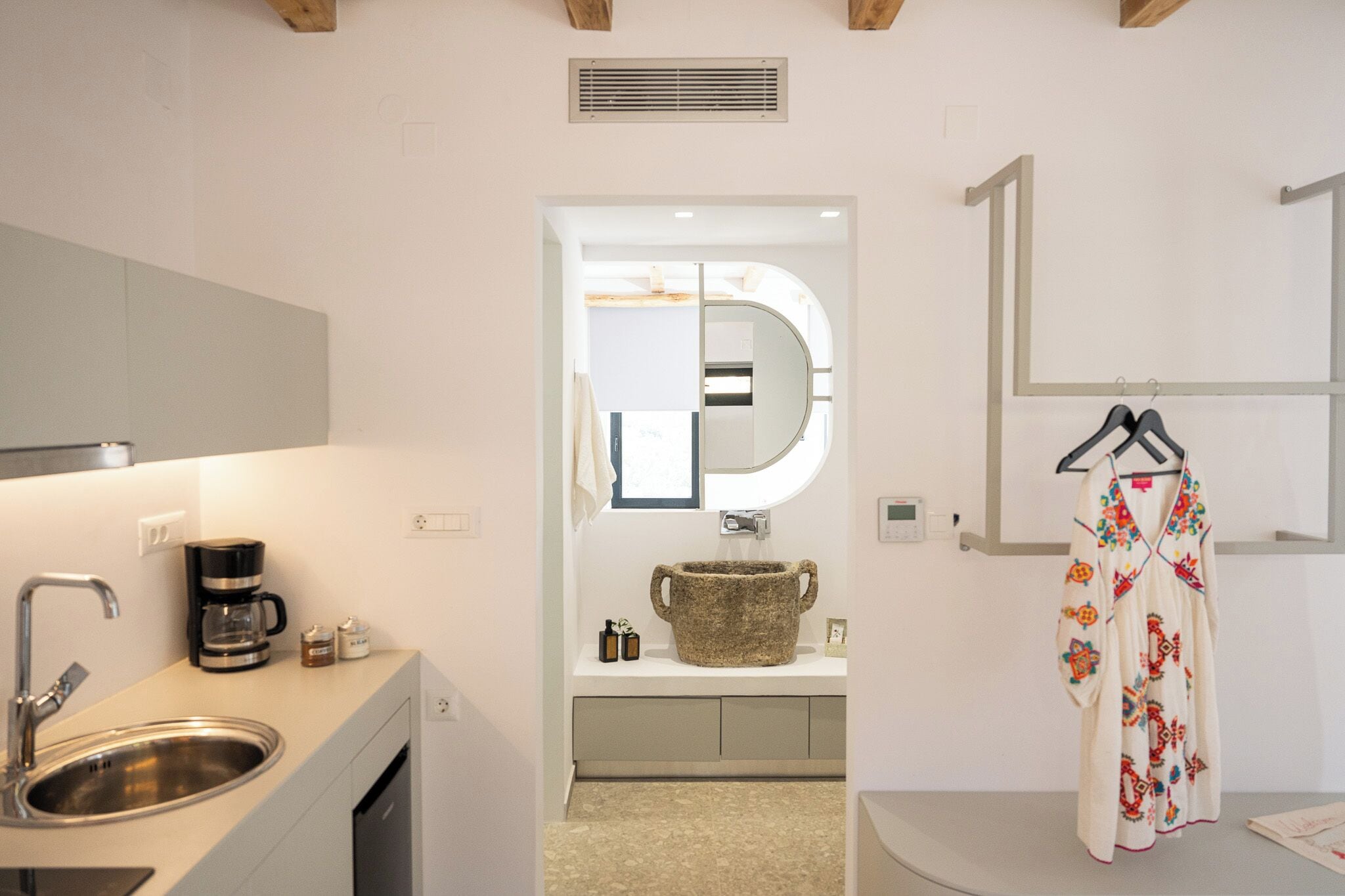 Une salle de bain moderne équipée d’un lavabo, d’une machine à café et d’un miroir.