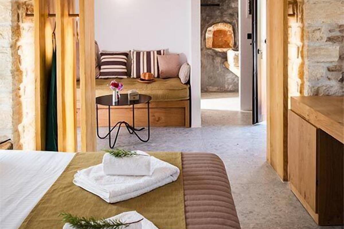 Een gezellige kamer met een stenen boog, een bed met witte handdoeken, een houten bank en een stenen openhaard.