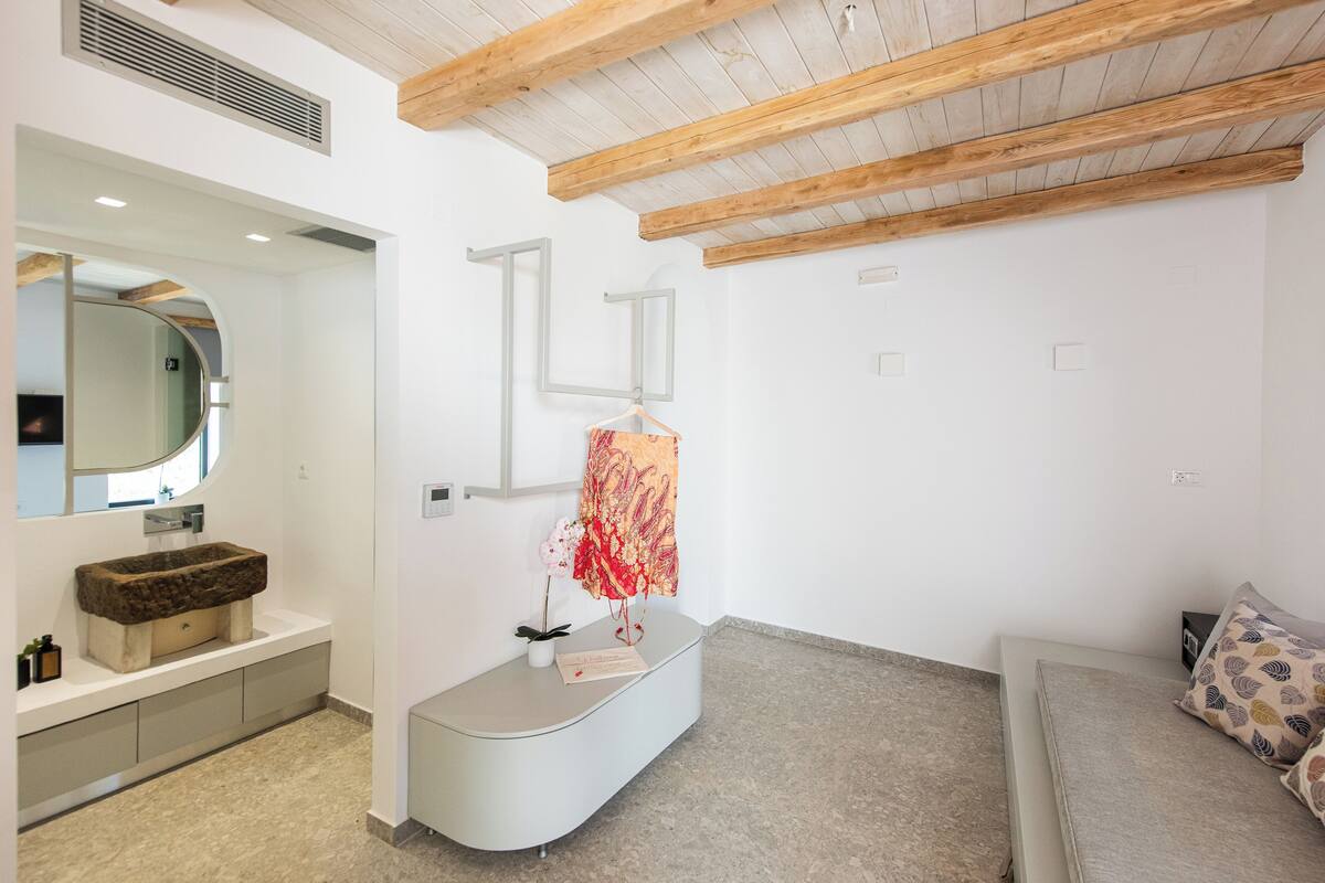 Een moderne badkamer met een bijzondere stenen wasbak, een spiegel en een houten plafond.