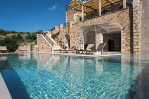 Un bâtiment en pierre doté d’une piscine, d’un espace extérieur aménagé et d’un escalier menant à un niveau supérieur.