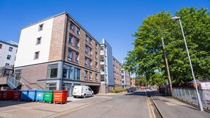 Un immeuble à plusieurs étages doté d’une architecture moderne, caractérisé par un mélange de façades en brique et en verre.