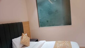 A hotel room with a bed, a nightstand, a window, and a headboard. - Sampanna Inn (Varanasi)