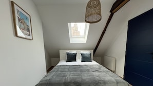 Un dormitorio con cama, ventana, un cuadro en la pared y una puerta.