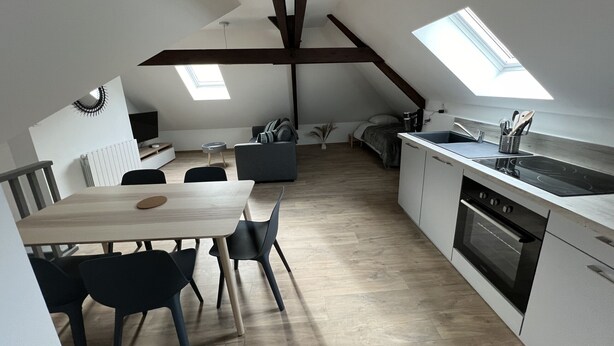 Una cocina moderna con comedor, tragaluces y un dormitorio en entrepiso.
