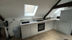 Una cocina compacta con ventana, horno empotrado y lavavajillas.