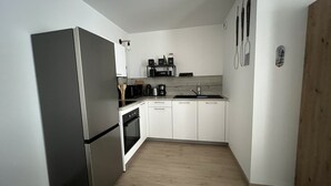 Una cucina compatta con frigorifero, forno, microonde, macchina del caffè e lavello.