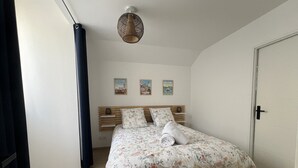 Una camera da letto con un letto, un comodino, un lampadario e tre quadri appesi al muro.