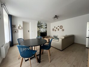 Una sala de estar moderna con comedor, sofá y televisor.