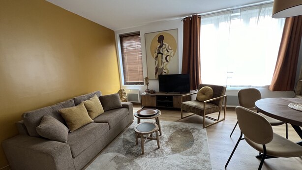 Ein Wohnzimmer mit einer Couch, einem Couchtisch, einem Fernseher und einem Essbereich mit Stühlen und einem Tisch.