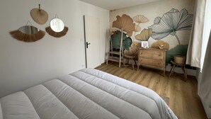 Ein Schlafzimmer mit Bett, Schminktisch, Spiegel und einer Wand mit floralem Wandbild.