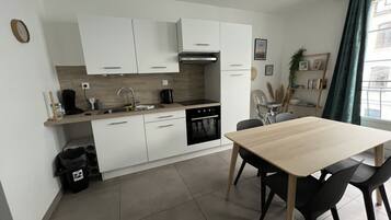A modern kitchen with white cabinets, a wooden countertop, and a dining area with a table and chairs.