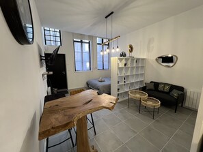 Ein moderner Wohnraum mit Küchenzeile, Esstisch, Sofa und Bücherregal.