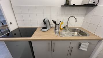 Una cucina moderna con piano cottura integrato, lavello con scolapiatti e un piccolo ripiano sopra il lavello.