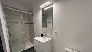 A modern bathroom with a glass shower enclosure, a white sink, and a toilet.