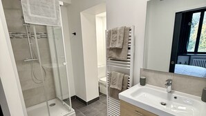 Ein modernes Badezimmer mit Duschkabine aus Glas, Waschbecken mit Spiegel und Handtuchhalter.