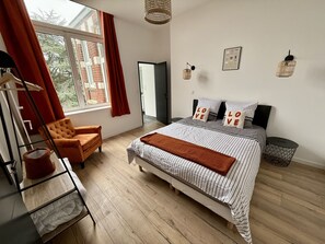 A bedroom with a bed, a chair, a wardrobe, and a window with curtains.