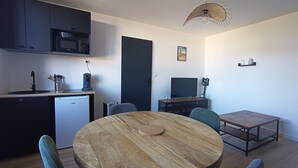 A compact kitchen with a dishwasher, microwave, and coffee machine. There is a dining area with a round wooden table and chairs. - Le Calais Wilson 6 : Appt 4p (Calais)