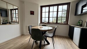 A modern kitchen with a dining area, wooden flooring, and a large window providing natural light. - Le Calais Wilson 6 : Appt 4p (Calais)
