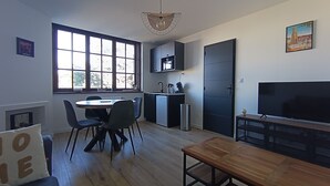 A compact living space with a dining area, kitchenette, and a TV. - Le Calais Wilson 6 : Appt 4p (Calais)