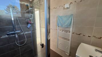 Une salle de bain avec une douche à parois de verre, un lavabo blanc et un porte-serviettes.