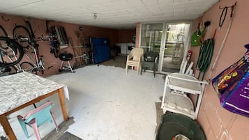 Eine Garage mit Tisch, Stühlen, einem Fahrrad und einer Hundeschüssel.