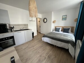 A modern bedroom with a bed, bedside table, and a view of the kitchen. - L'Esprit Maritime - 2p, downtown, Place Dalton (Boulogne-sur-Mer)