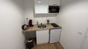 Une petite cuisine équipée d’un four à micro-ondes, d’un évier et d’un petit réfrigérateur.