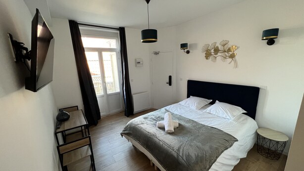 Une chambre à coucher moderne avec un lit, des tables de chevet, un bureau et une fenêtre.