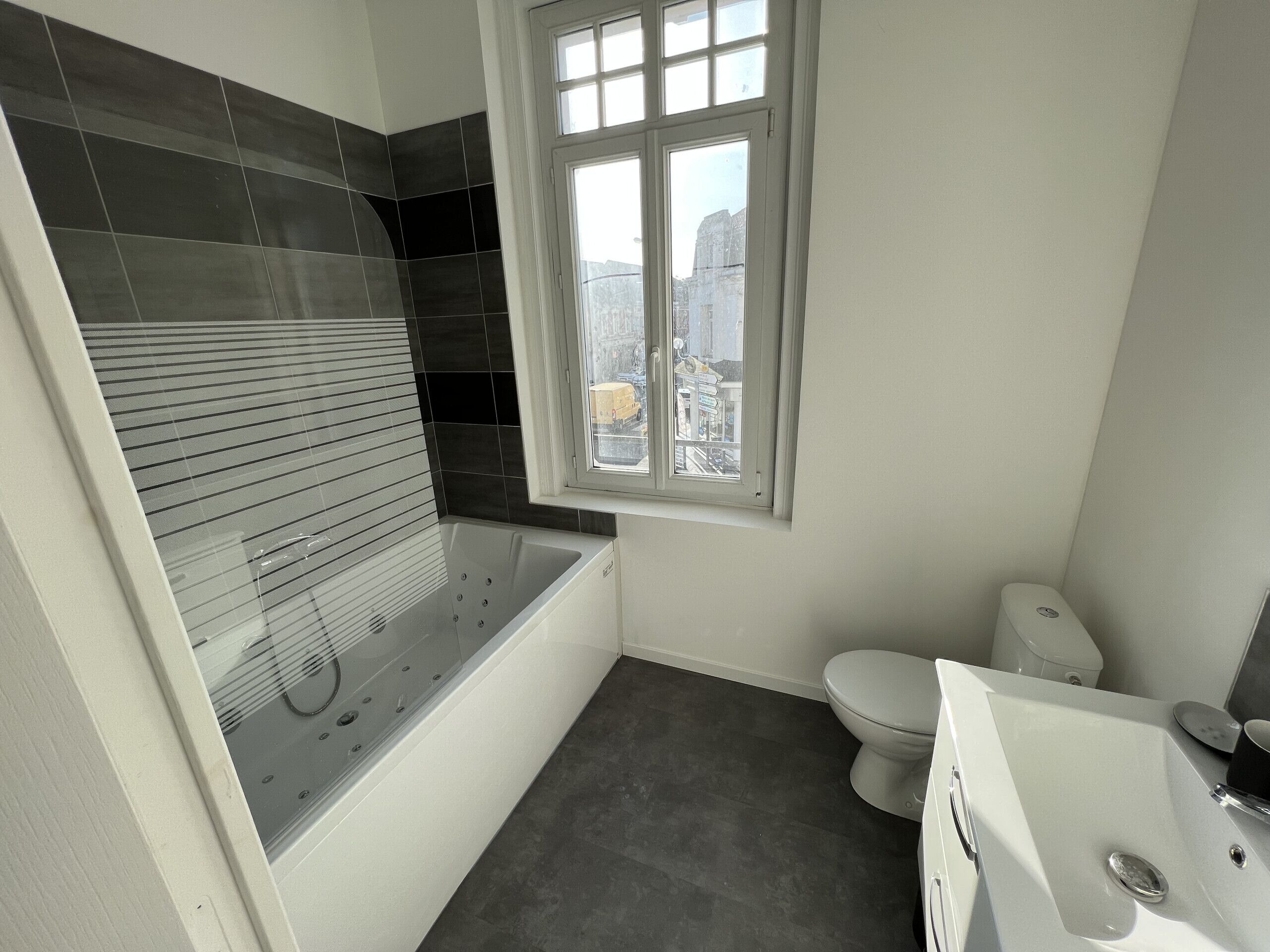 Ein modernes Badezimmer mit Badewanne, Toilette und Fenster.