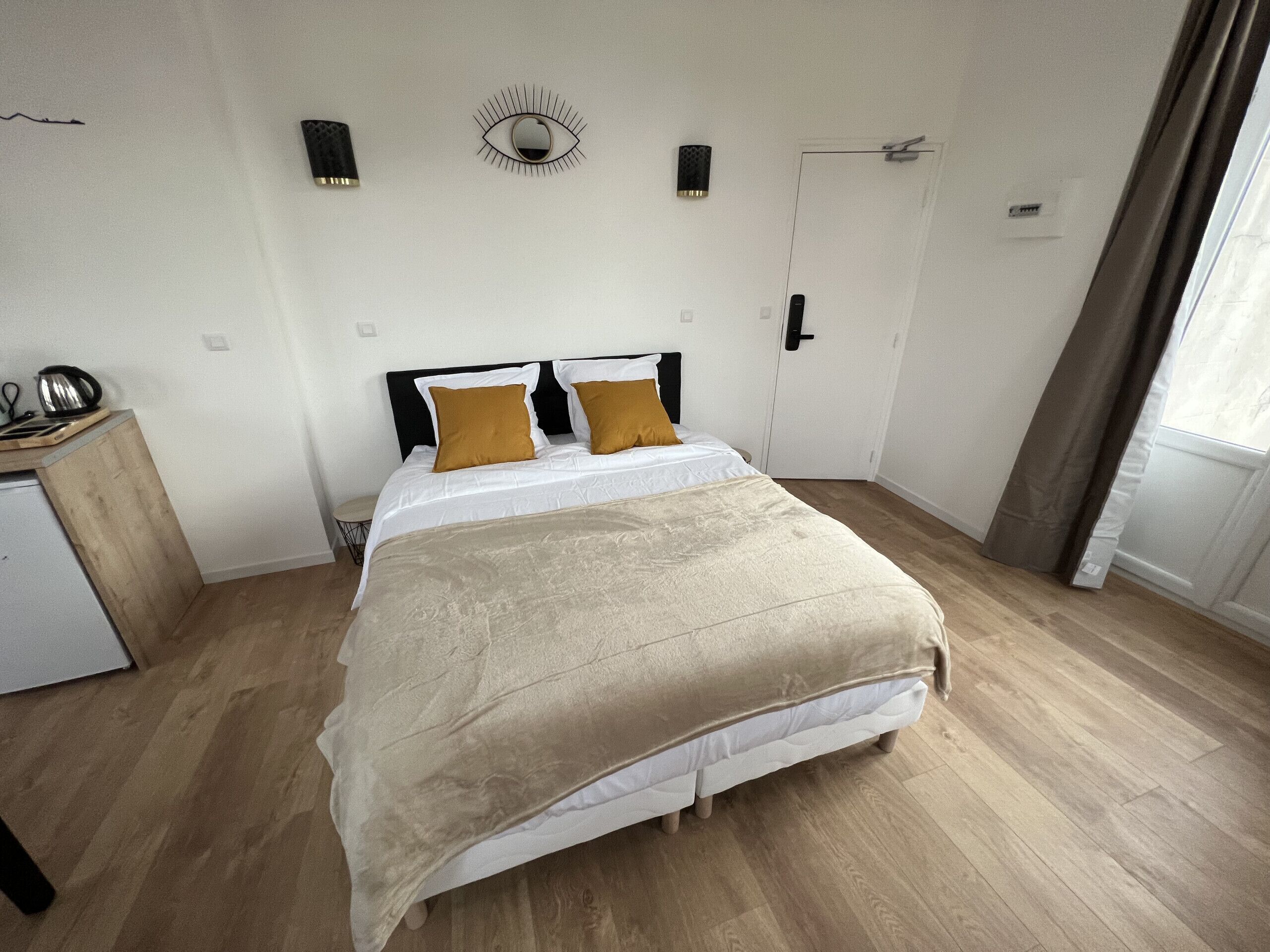 A bedroom with a bed, a bedside table, a mirror, and a door.