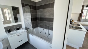 A modern bathroom with a bathtub, a sink, and a mirror. - La Suite Balnéo - 2p downtown Liévin (Liévin)